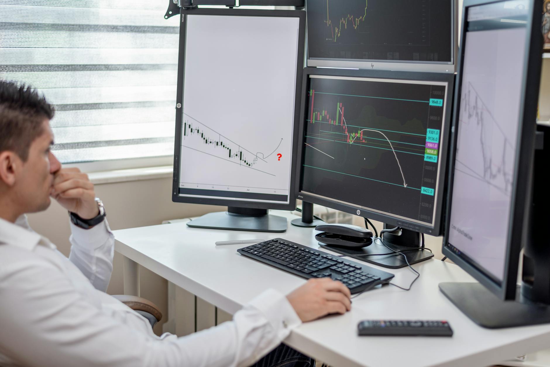 Data analyst at a desk with two monitors showing spreadsheets