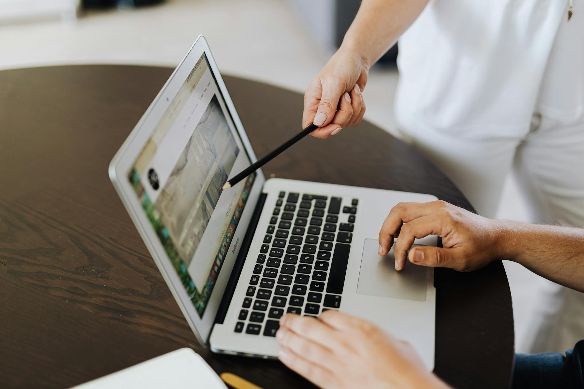 Person pointing at a laptop screen during a PowerPoint animation tutorial