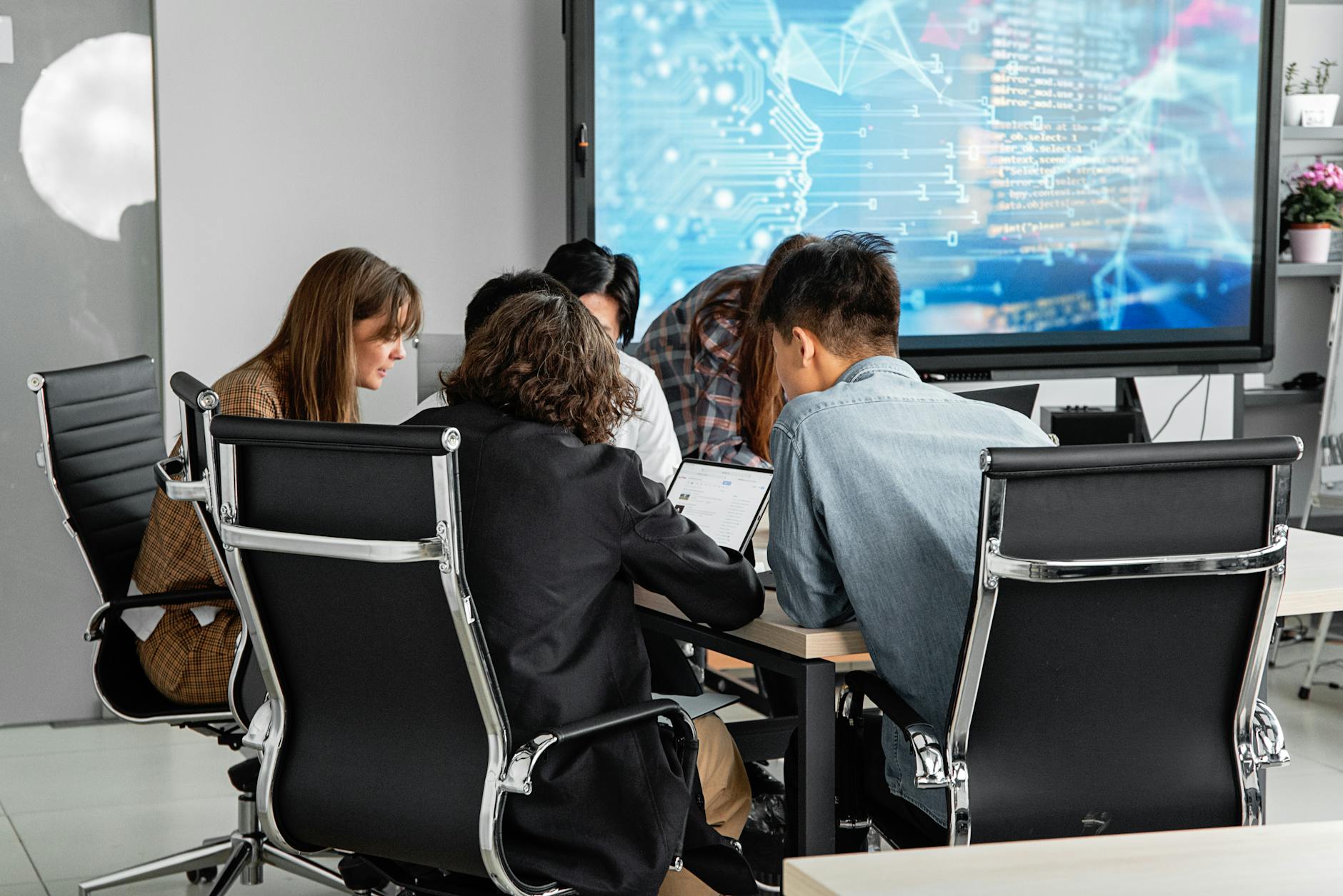 Colleagues reviewing Copilot-generated meeting minutes around a conference table with a screen