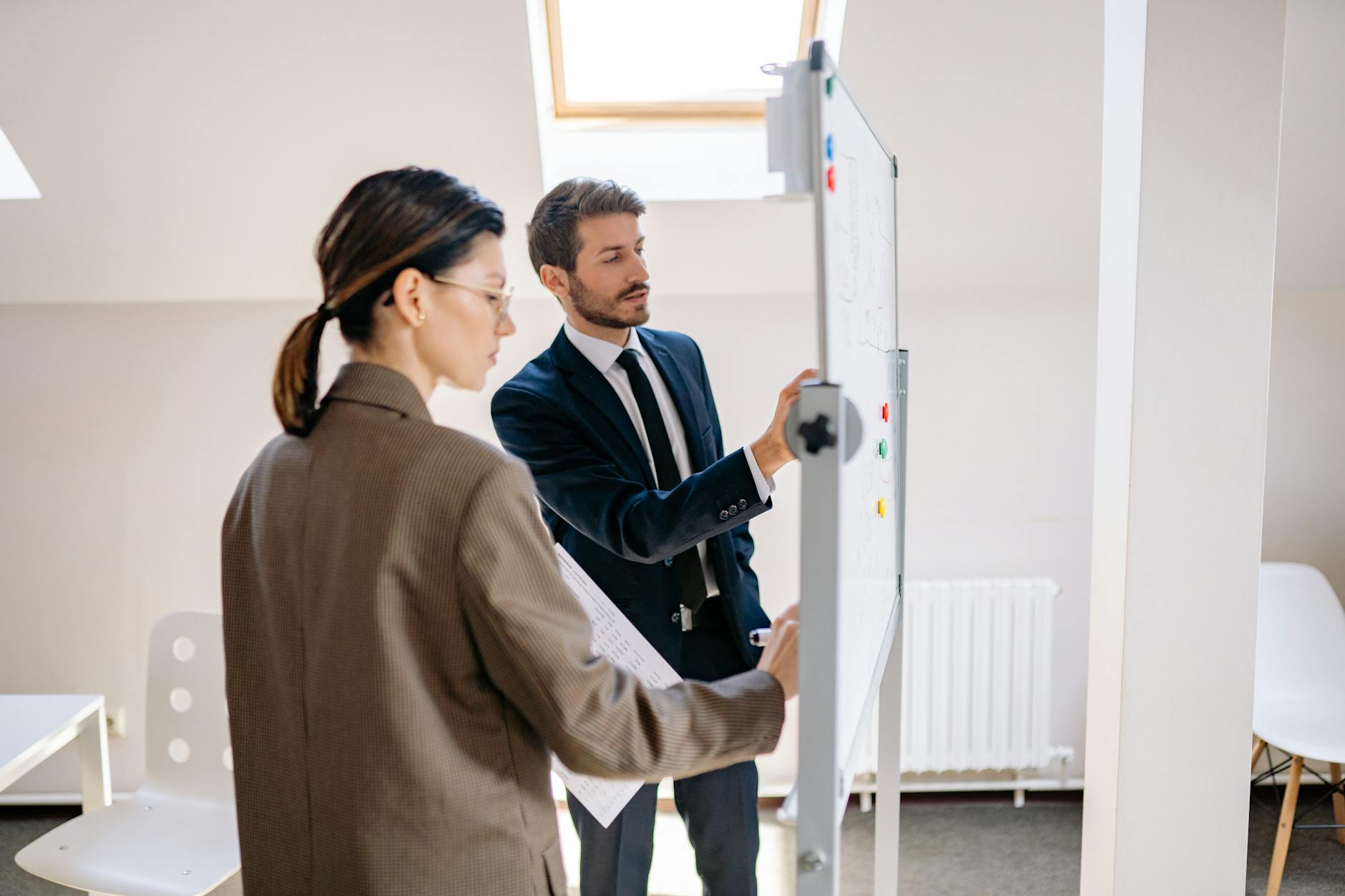 Business team comparing plans on a whiteboard in a meeting