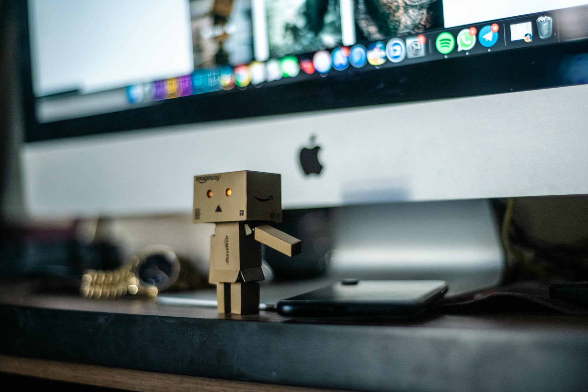 Cardboard robot sitting in front of a computer monitor representing desktop RPA