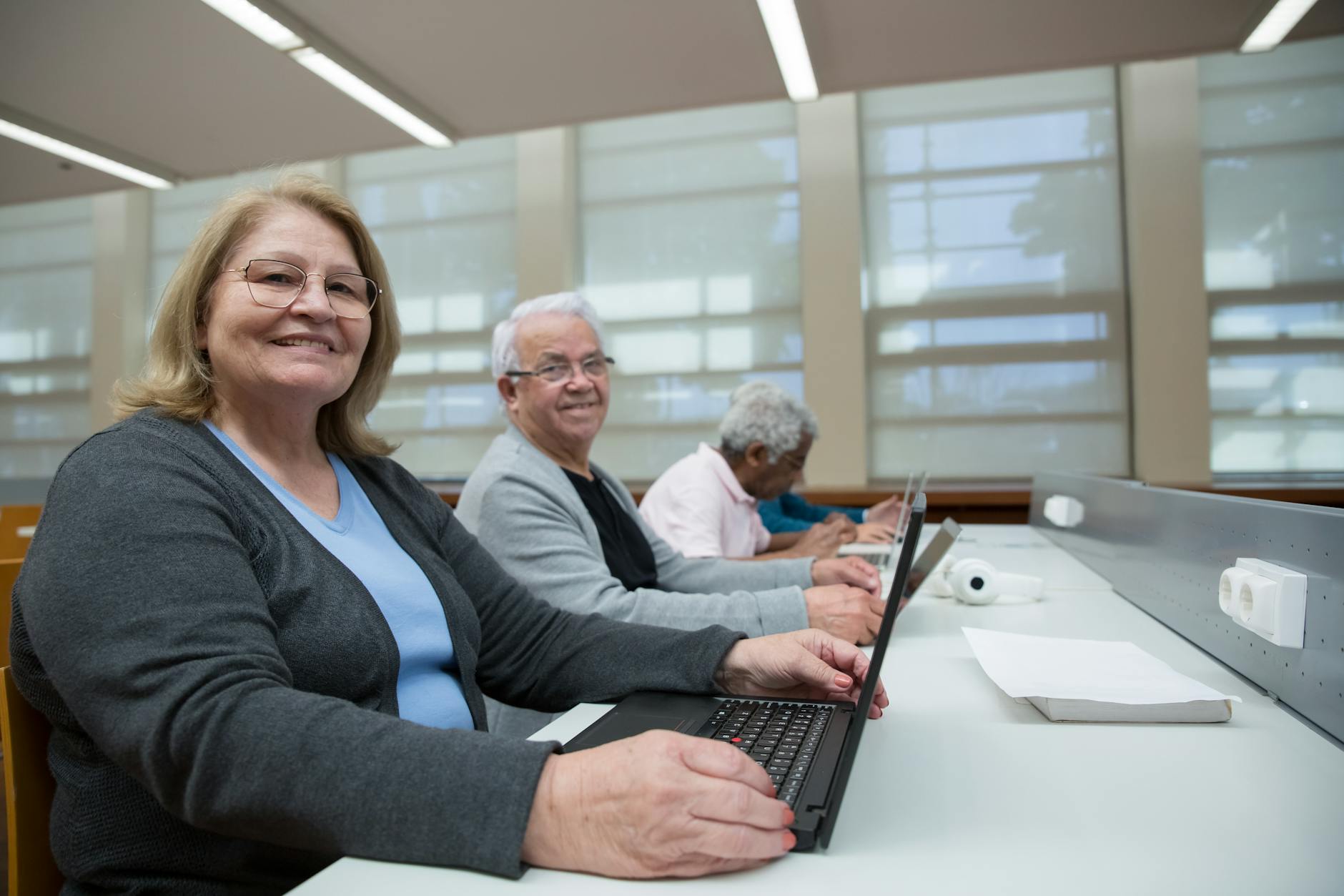 Adult learners working on laptops in a Singapore training room studying Power BI